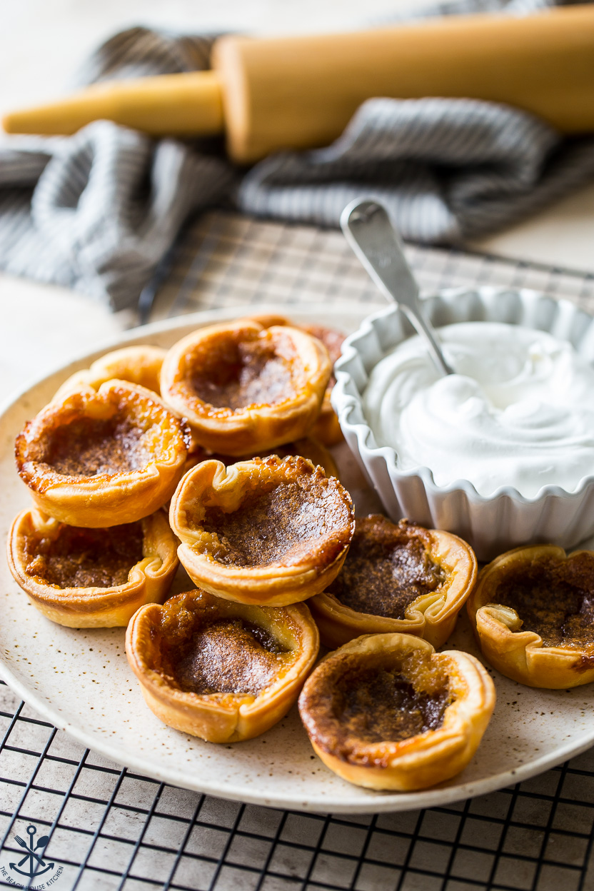 A plate of butter tarts with a bowl of whipped cream