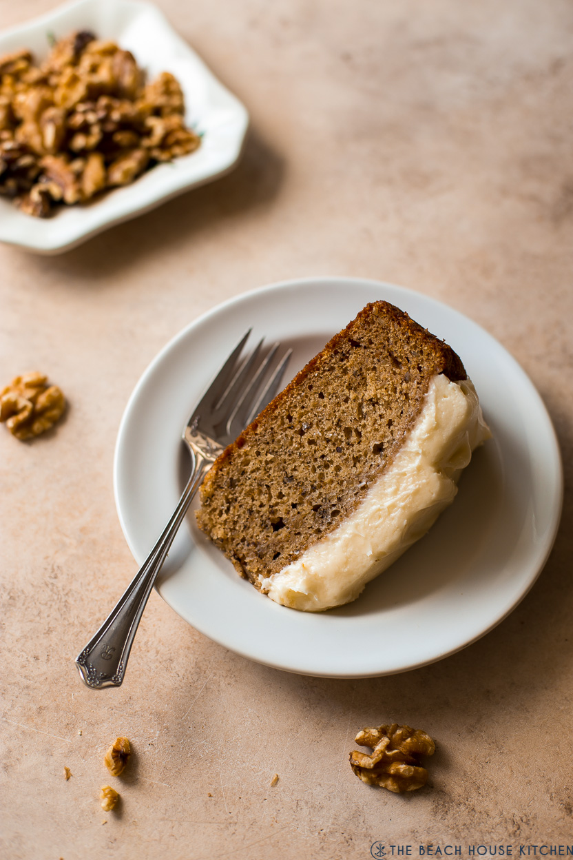 A slice of maple walnut cake on a white plate with a fork