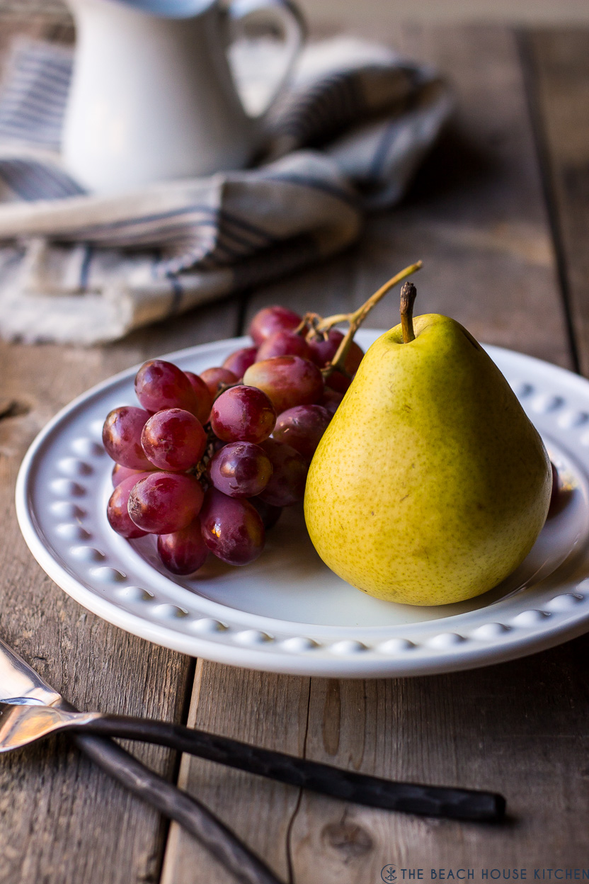 A photo of a yellow pear and grapes on a white plate