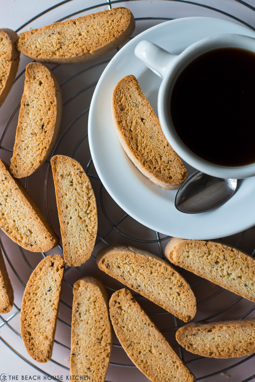 Anise biscotti on a round wire rack with a cup of coffee on a white saucer
