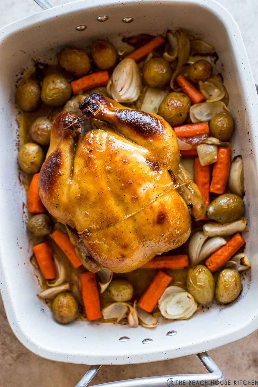 Overhead photo of a roast chicken with veggies in a roasting pan