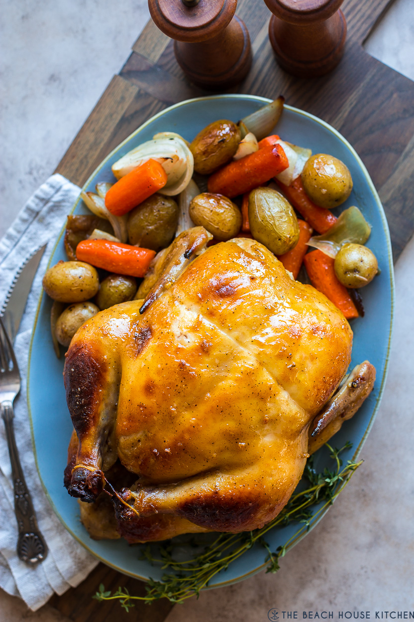 Overhead photo of a roast chicken on an oval light blue platter