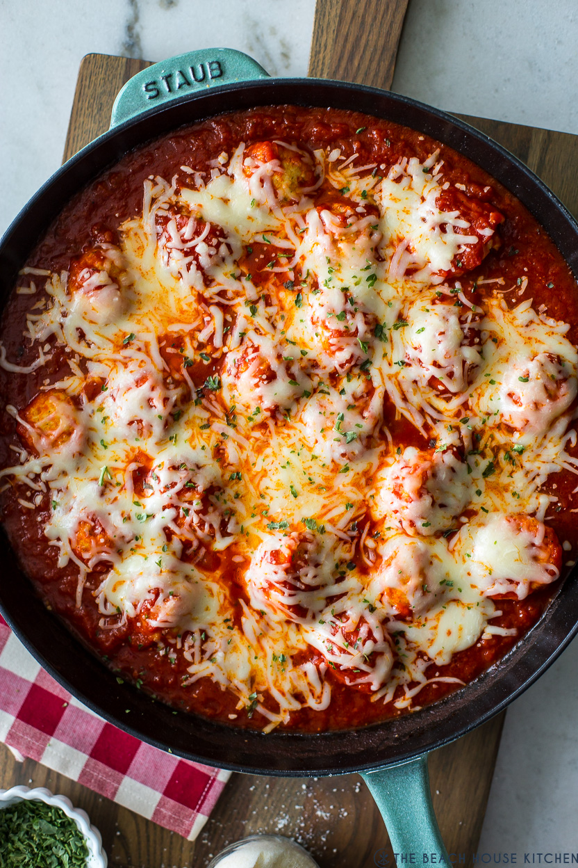 Overhead photo of a skillet of meatballs topped with shredded cheese.