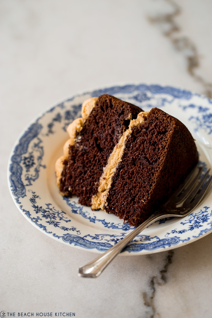 Up close photo of a piece of chocolate cake on a blue and white plate with a fork