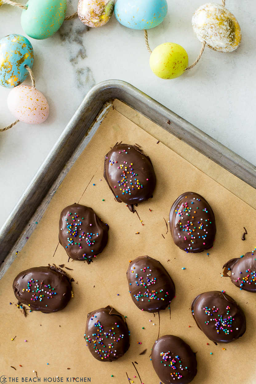 Chocolate covered peanut butter eggs on a parchment-lined baking sheet