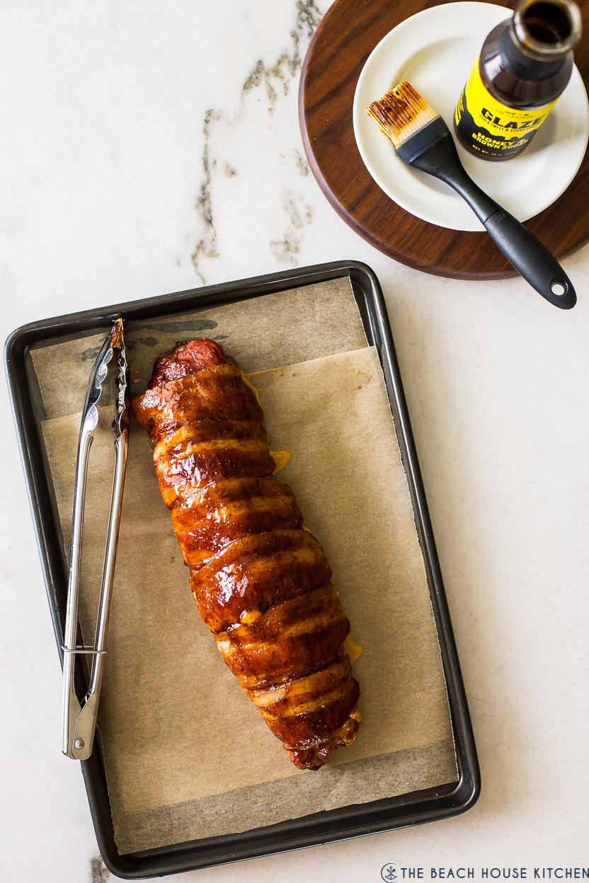 Overhead photo of a bacon wrapped pork tenderloin on a baking sheet