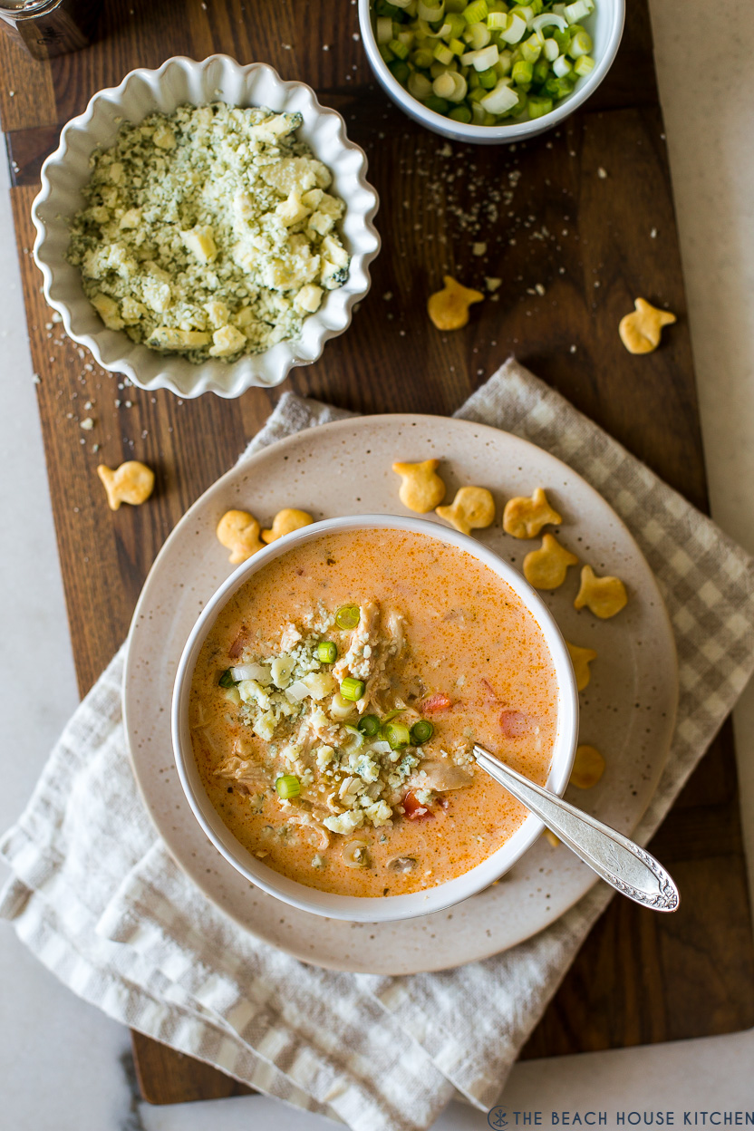 Overhead photo of a bowl of buffalo chicken soup with a bowl of blue cheese crumbles