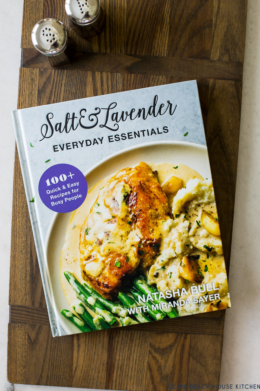 Overhead photo of a Salt & Lavender Everyday Essentials Cookbook on a wooden board