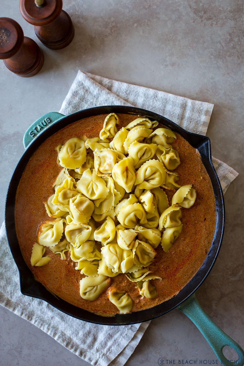 Overhead photo of a skillet of sauce topped with cooked tortellini