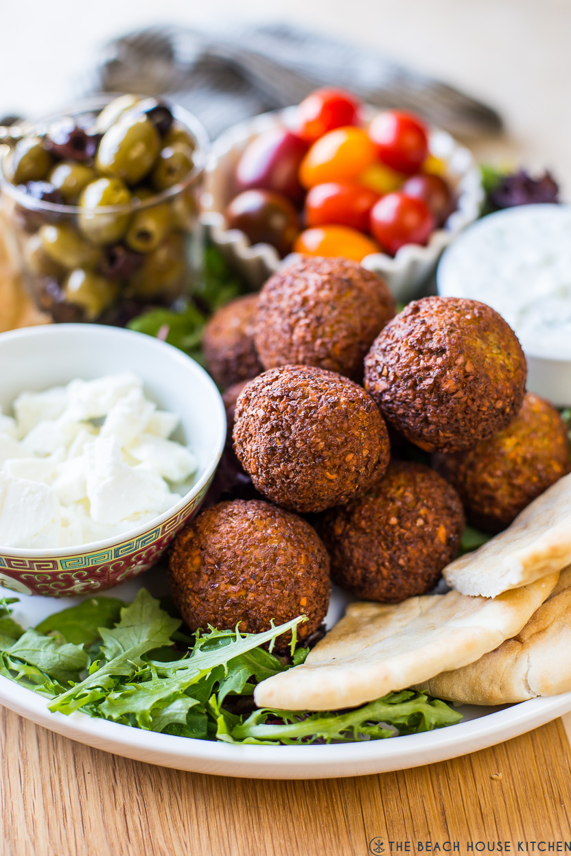 Up close photo of falafel balls on a platters with cheese and veggies