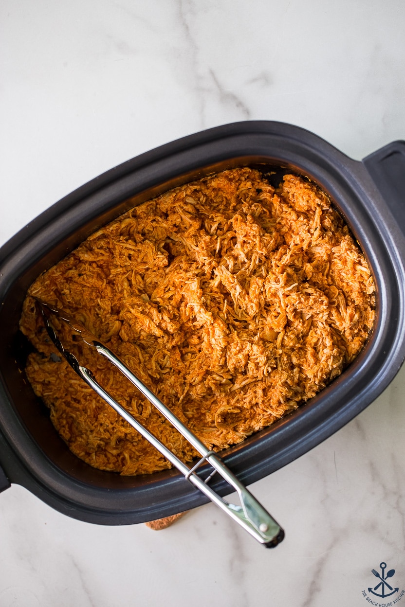 Overhead photo of a slow cooker of shredded buffalo chicken