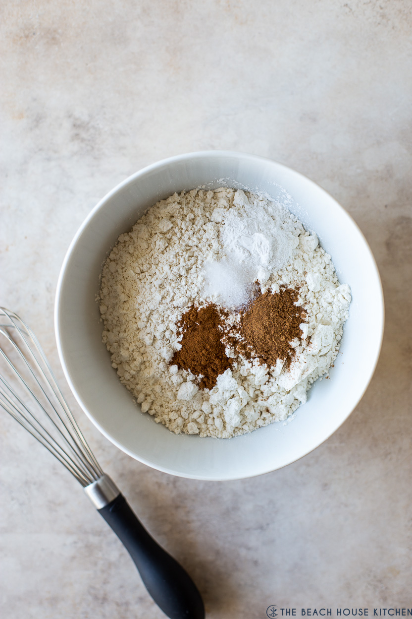 Overhead photo of a bowl of flour and spices with a whisk off to the side