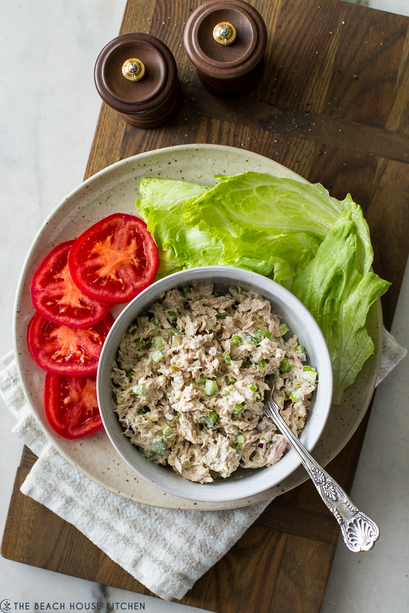 Overhead photo of a bowl of the best tuna salad recipe with tomatoes and lettuce off to the side