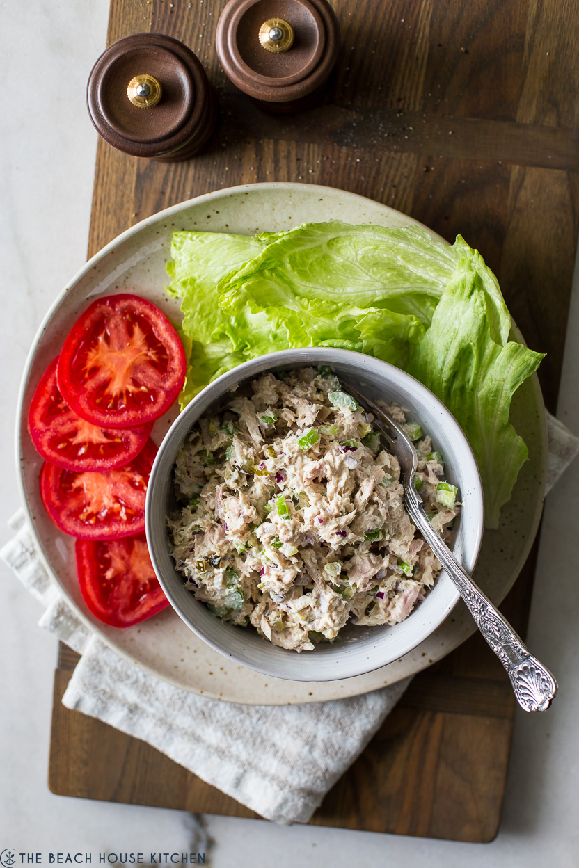 Overhead photo of a plate with tomato slices, iceberg lettuce and a bowl of the best tuna salad recipe