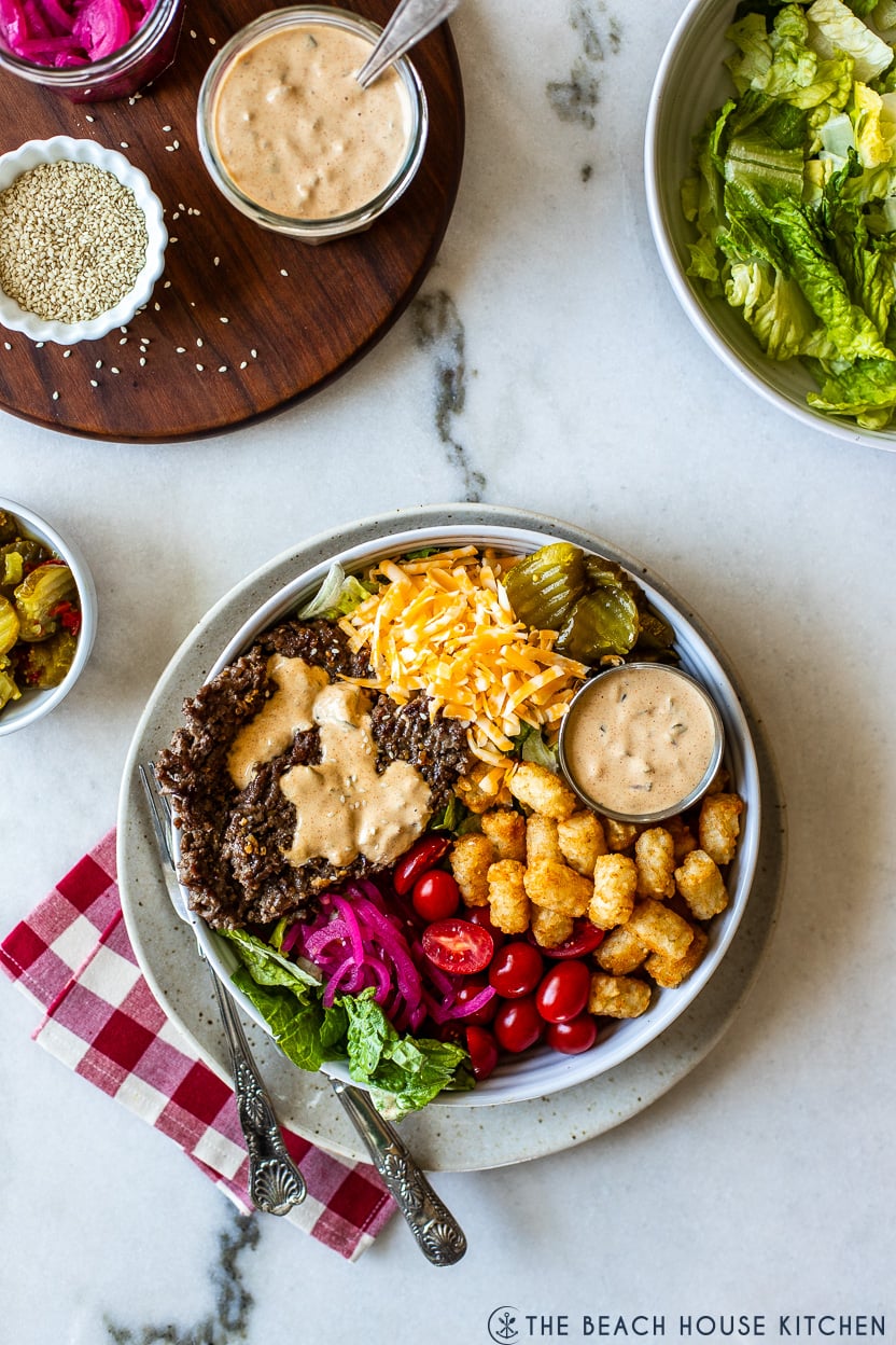 Overhead photo of a burger bowl filled with veggies, cheese and tater tots