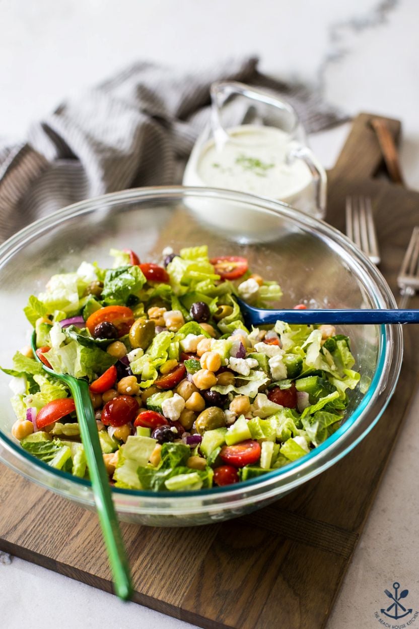 A Greek Chickpea Salad with Green Goddess Dressing in a glass bowl