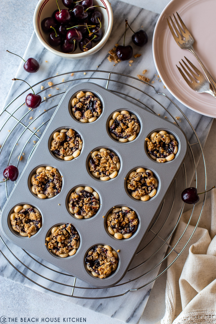 Overhead photo of a mini muffin pan filled with streusel topped cherry pie bites