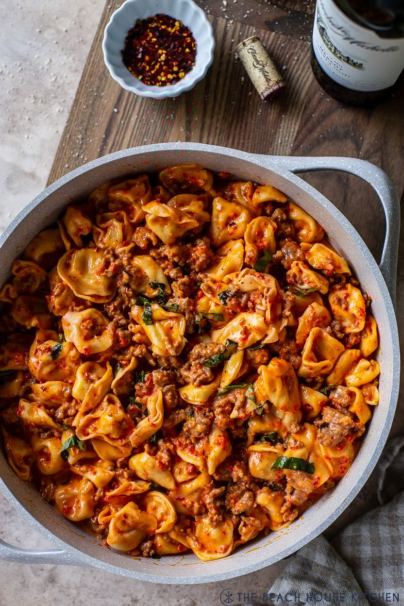 Up close overhead photo of a skillet of Roasted Red Pepper Tortellini Alfredo with Sausage