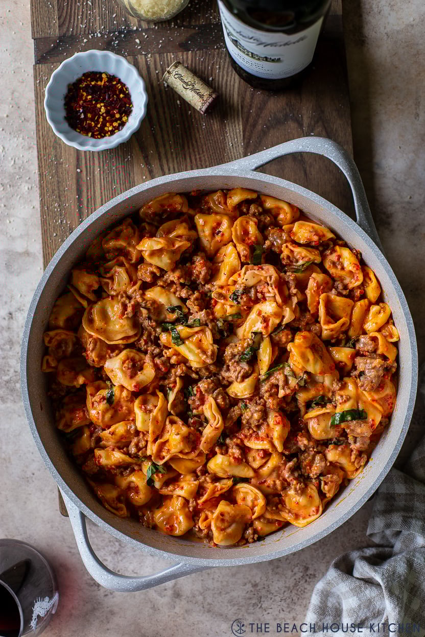 Overhead photo of a skillet of Roasted Red Pepper Tortellini Alfredo with Sausage