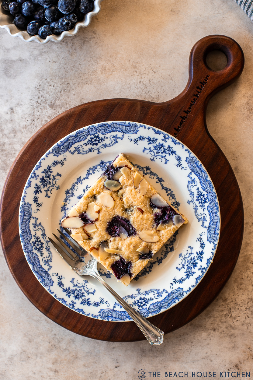 Overhead photo of a slice of a blueberry lemon blondie on a blue and white plate with a fork