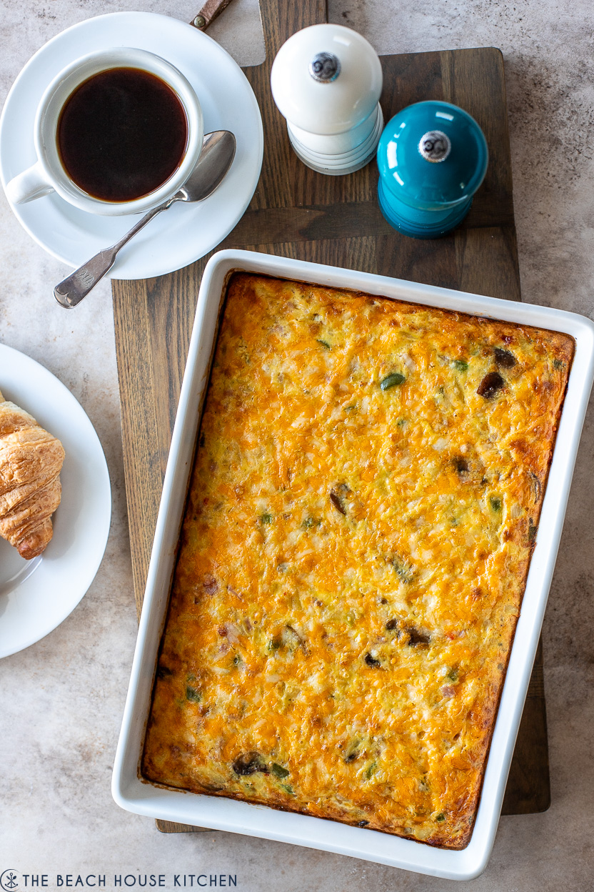 Overhead photo of a breakfast casserole in a white baking dish with a cup of coffee and salt and pepper shakers
