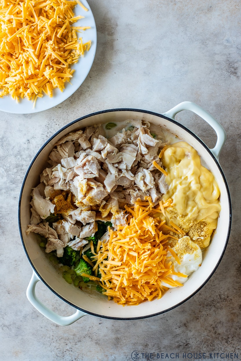 Overhead photo of a skillet filled with chicken broccoli, cream of chicken soup, sour cream and shredded yellow cheddar cheese