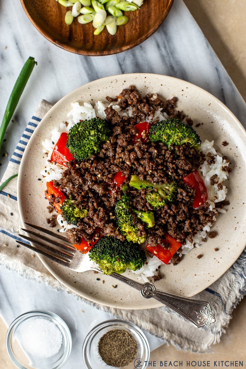 Very up close photo of a plate of beef, broccoli and red peppers over rice