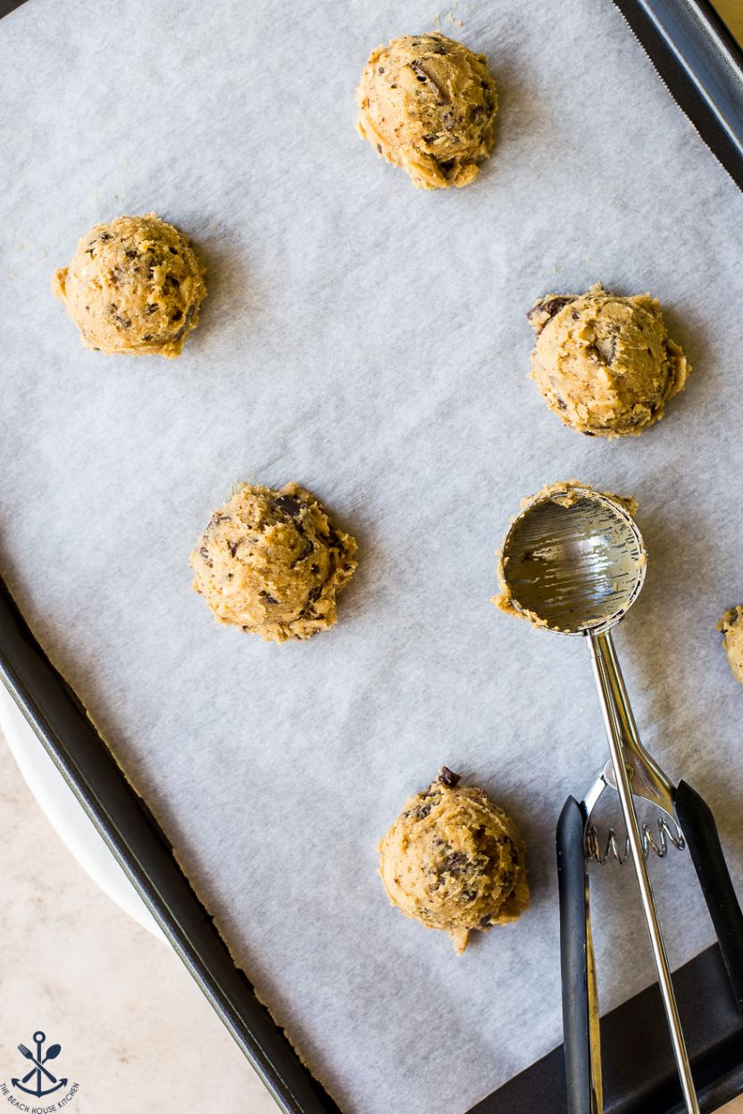 Overhead photo of scoops of cookie dough on a parchment-lined baking sheet