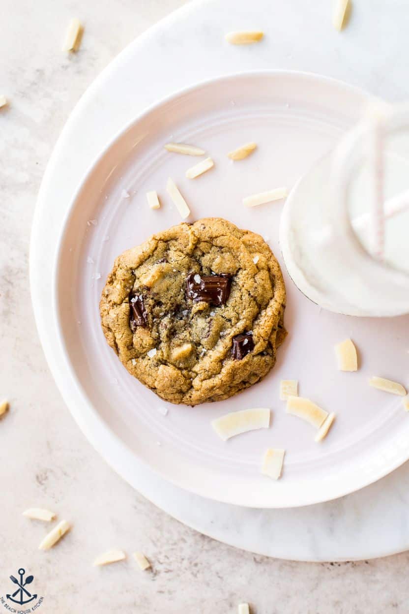 Overhead photo of an almond joy chocolate chip on a plate with some coconut flakes and a bottle of milk