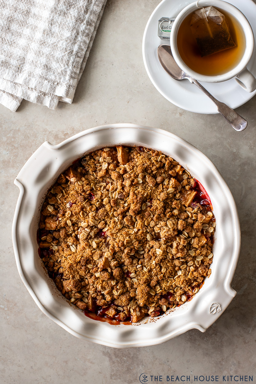 Overhead photo of an apple cranberry crisp and a cup of tea