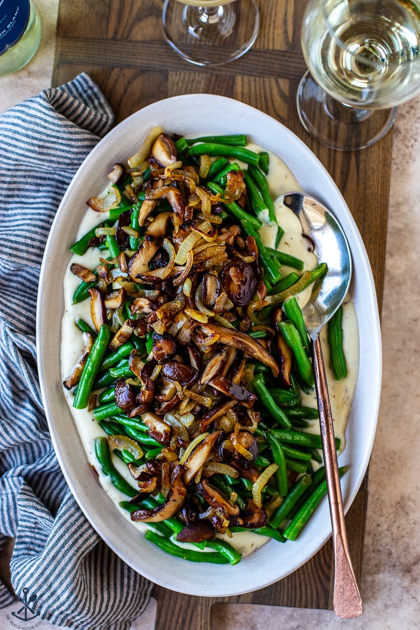 Up close overhead photo of an oval plate topped with green beans mushrooms and onions