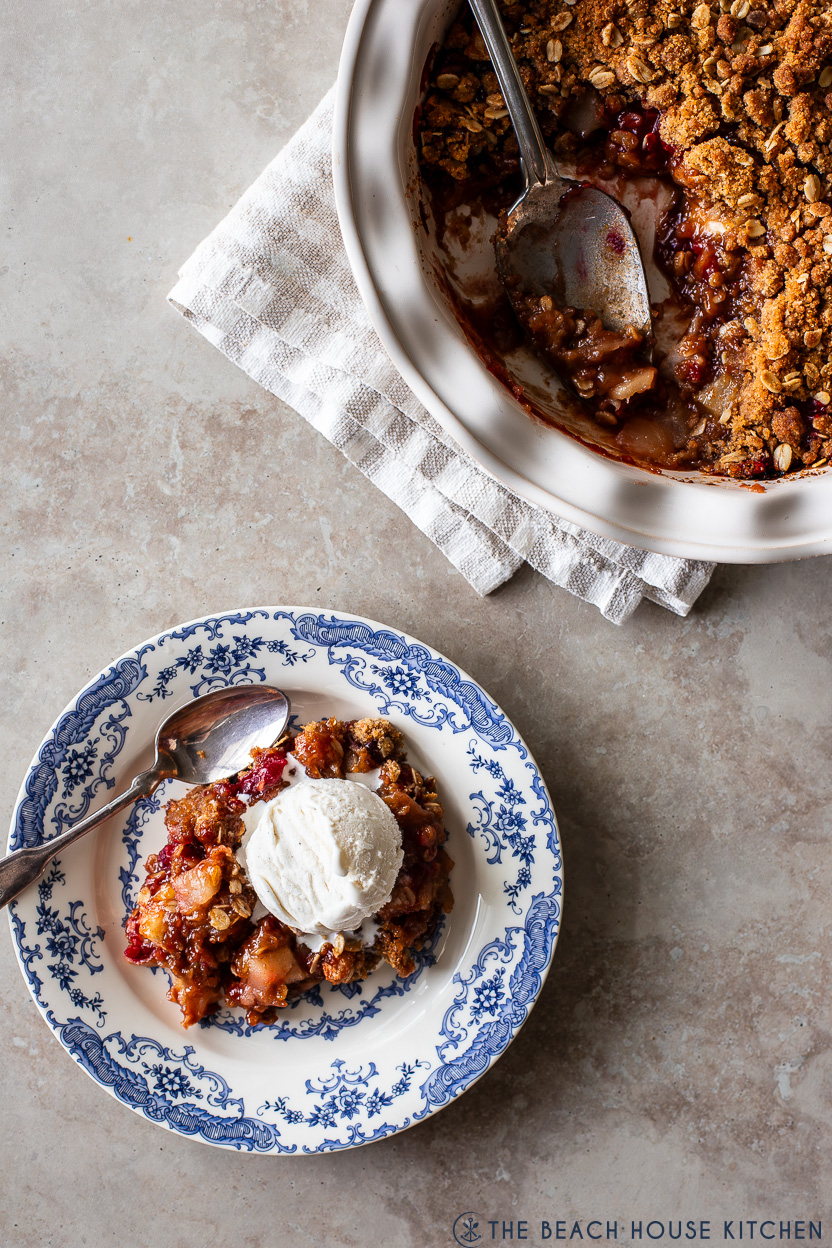 Overhead photo of a blue and white bowl filled with apple cranberry crisp topped with a scoop of vanilla ice cream