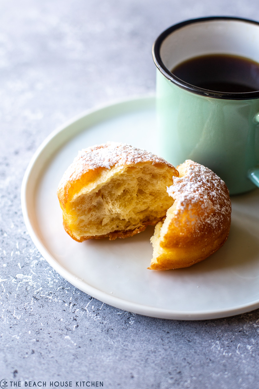Up close photo of a doughnut cut in half and a green coffee mug filled with coffee