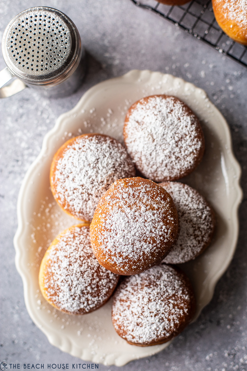 Overhead photo of a plate of six powdered doughnuts
