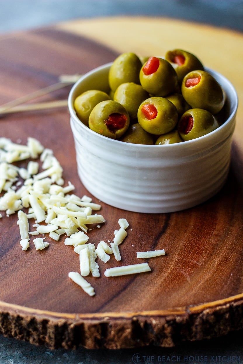 Up close photo of a bowl of olives with some shredded cheese