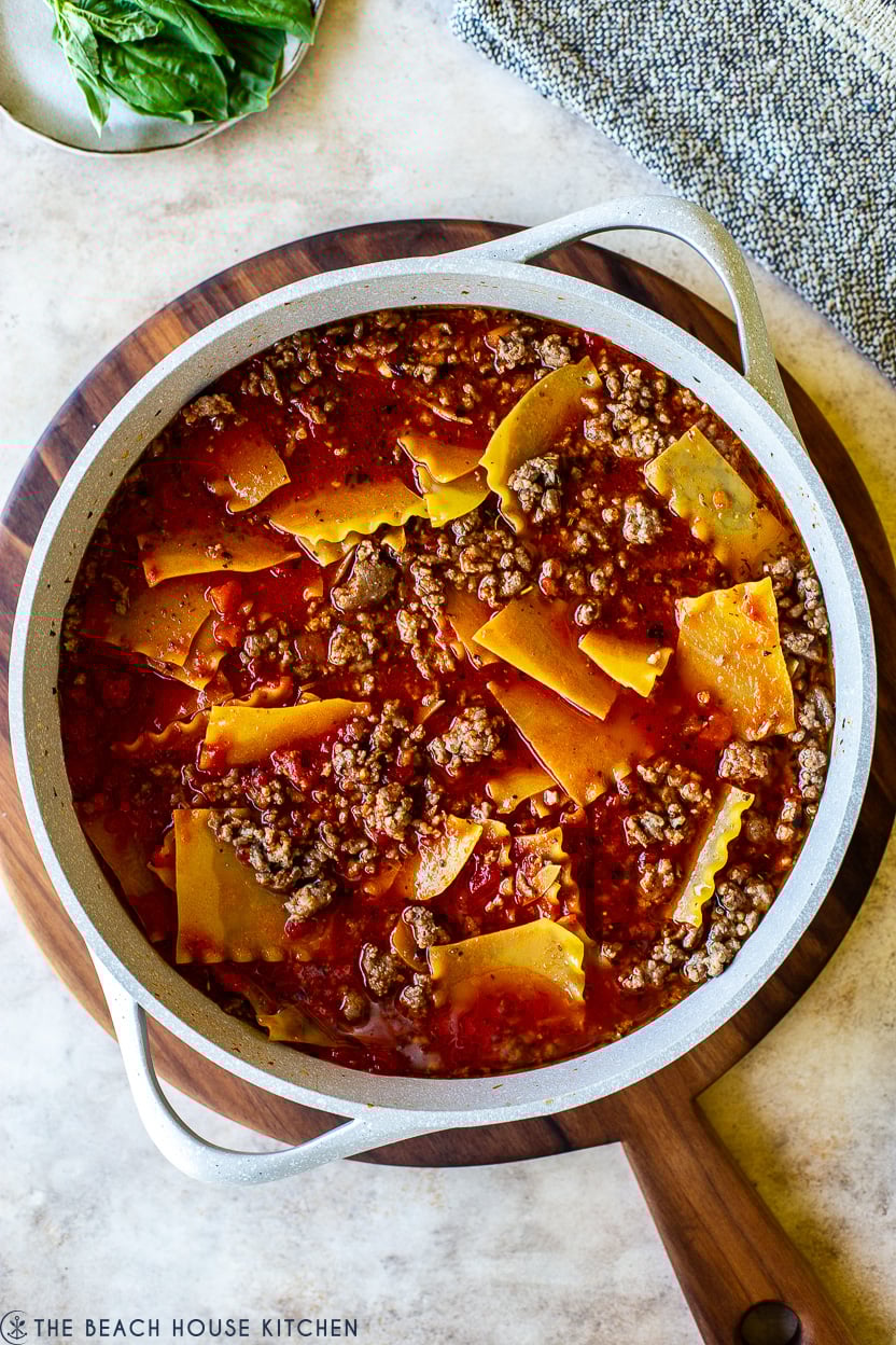 Overhead photo of a skillet with ground beef, tomato sauce and lasagna noodles