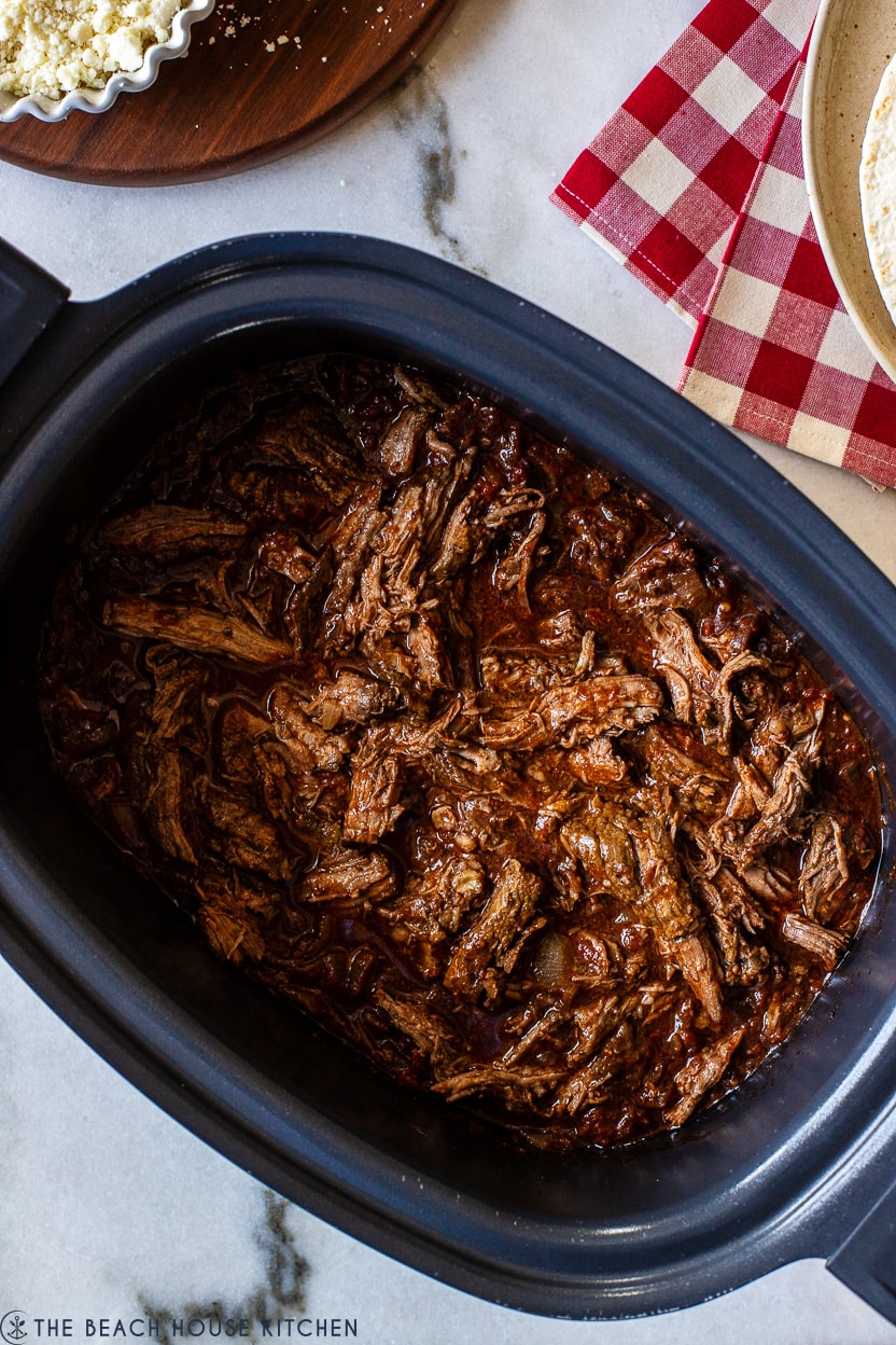 Up close overhead photo of a slow cooker of beef tinga