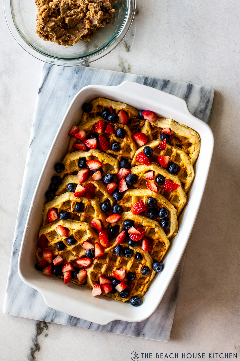 Overhead photo of a baking dish filled with waffles, strawberries and blueberries