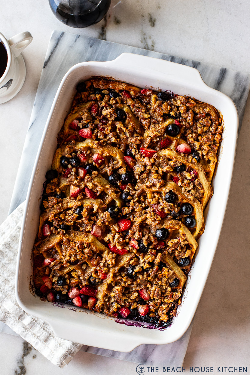 Overhead photo of a waffle breakfast casserole with berries in a white baking dish