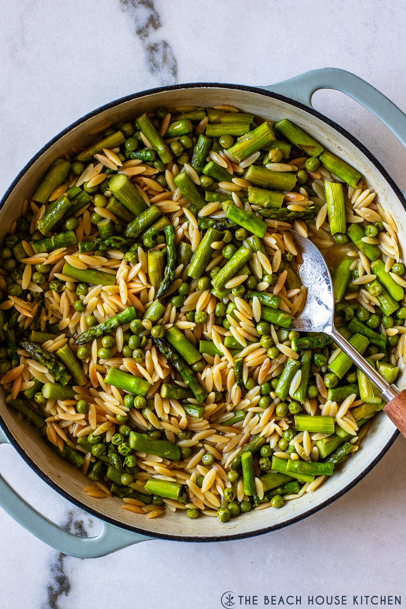 Overhead photo of a cast iron dish filled with asparagus and pea orzo