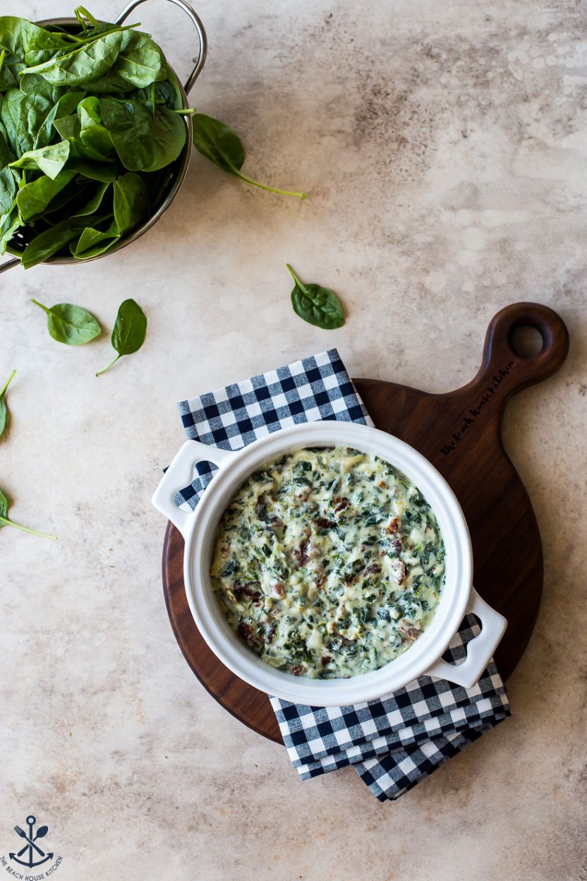 Overhead photo of a pre-baked spinaach dip with srtichokes and bacon