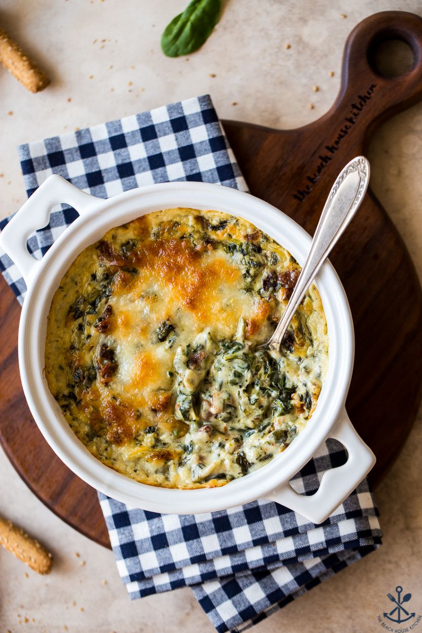 Up close overhead photo of a small baking dish of spincach artichoke dip with bacon