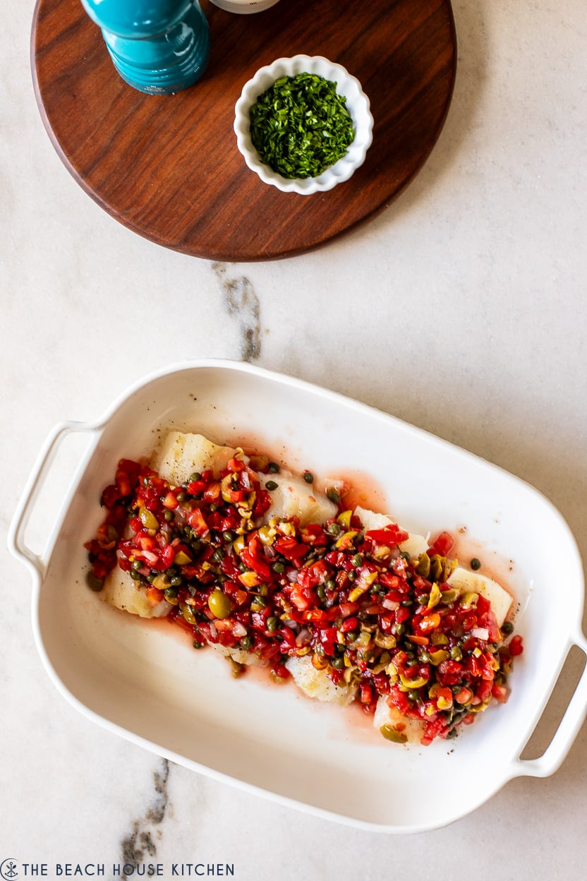 Overhead photo of pre-baked cod topped with a pico de gallo and olive mixture