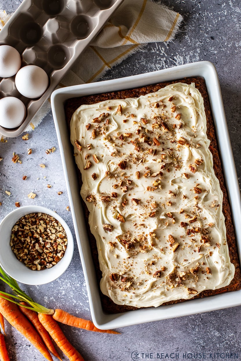 Overhead photo of a carrott cake topped with chopped pecans in a white baking dish