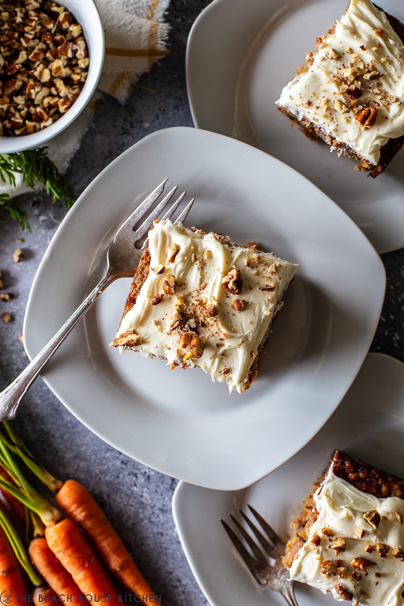 Overhead photo of square piece of carrot cake on a white plate with a fork