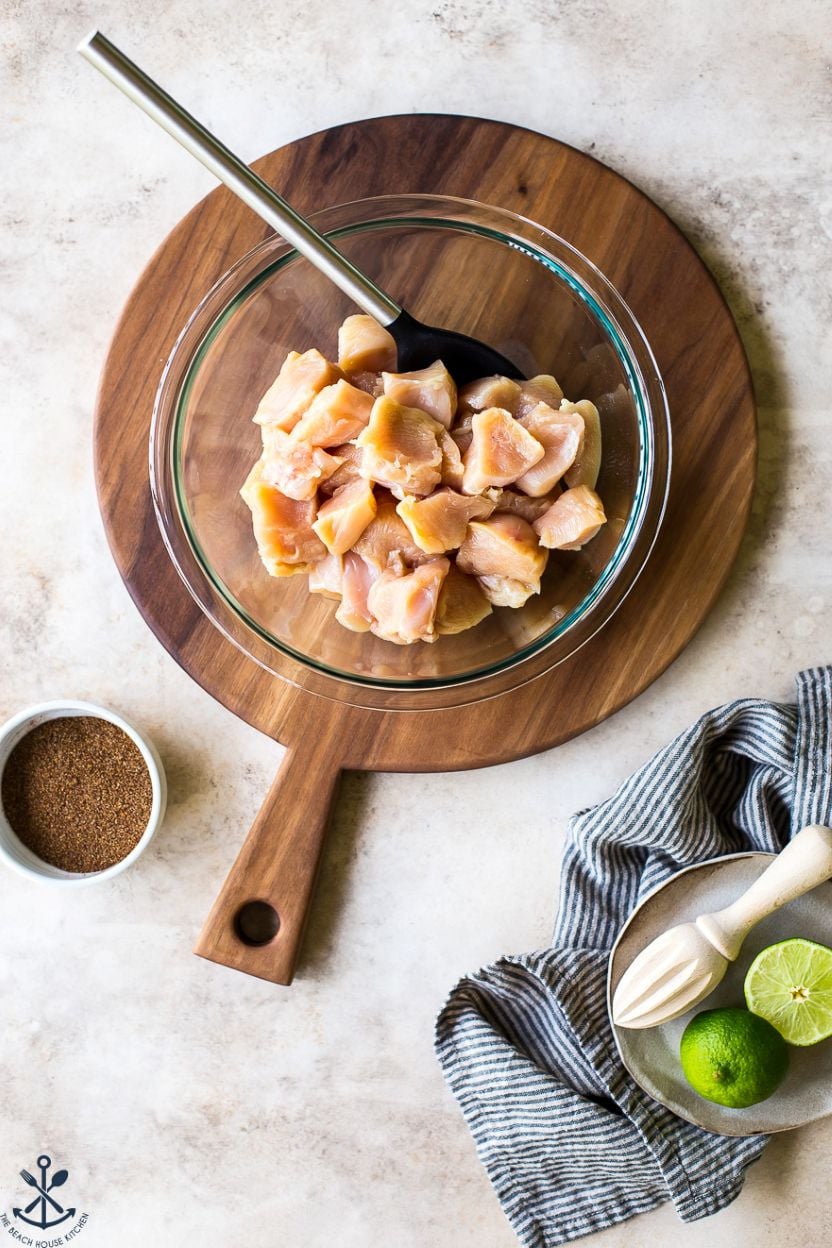 Overhead photo of a glass bowl filled with raw chicken pieces