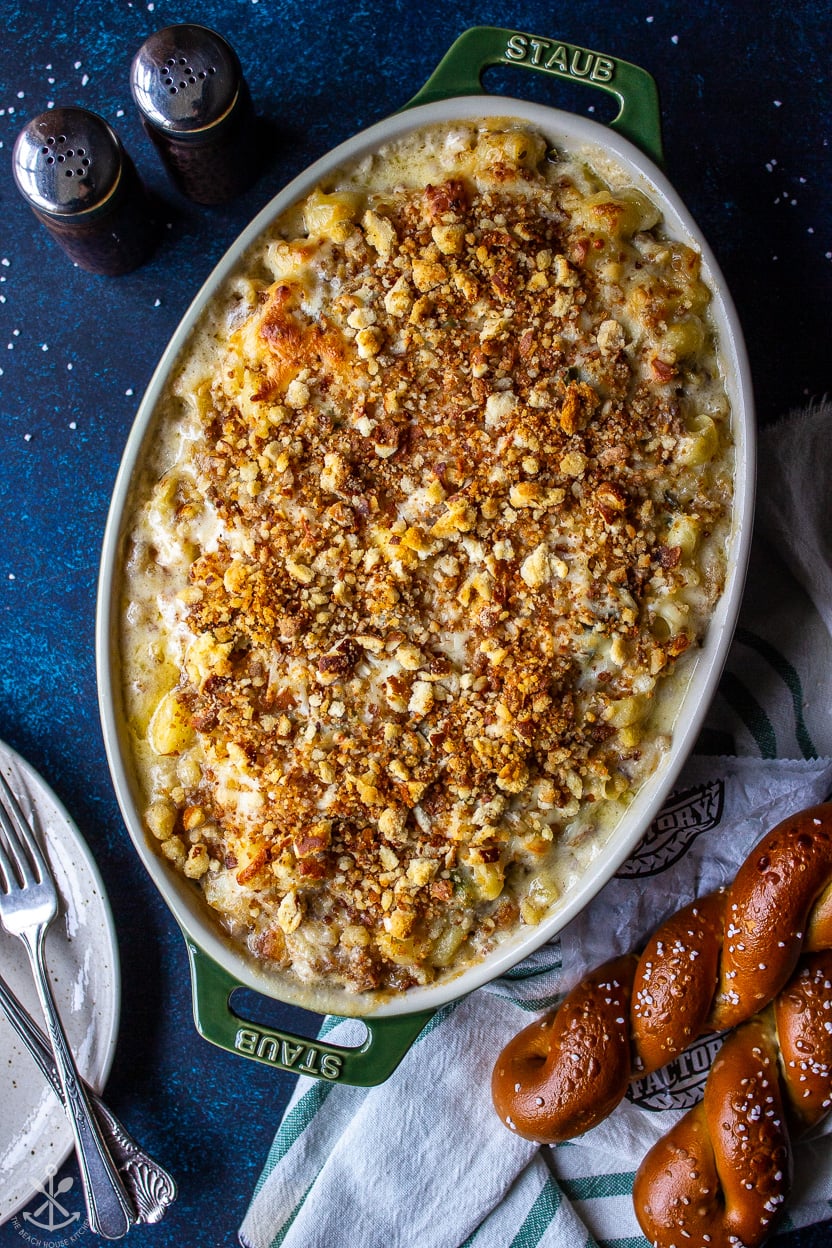 Overhead photo of a green oval baking dish filled with a macaroni and cheese topped with pretzel crumbs