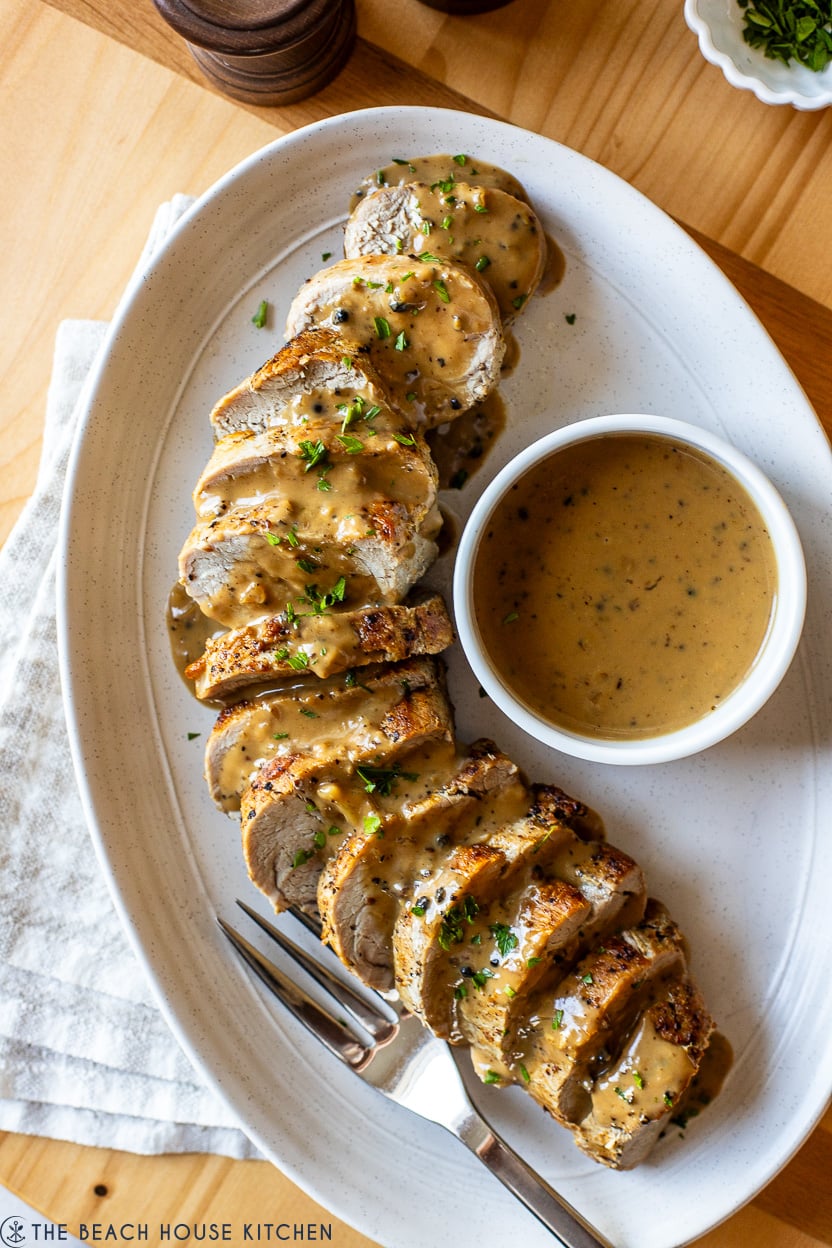 Up close overhead photo of Pork Tenderloin with Peppercorn Sauce on an oval platter