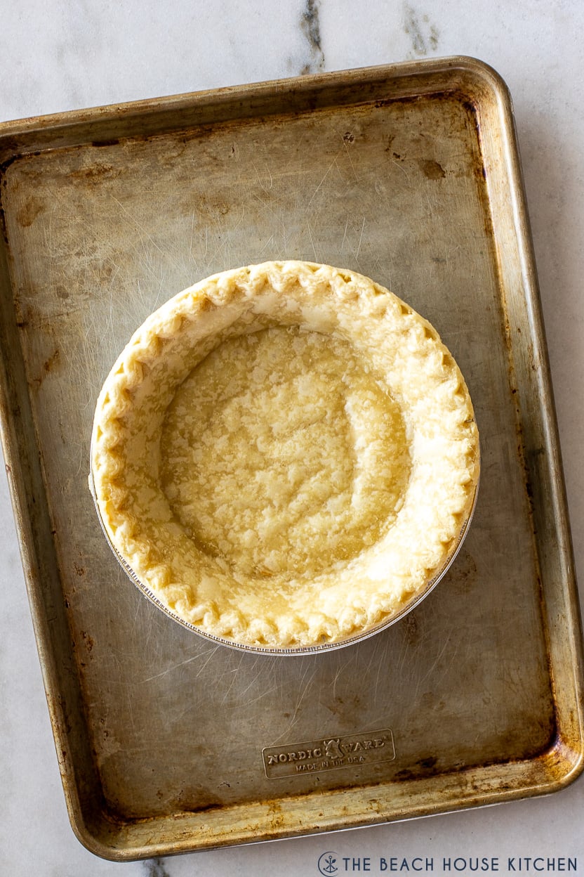 Overhead photo of a partially baked pie crust on a baking sheet