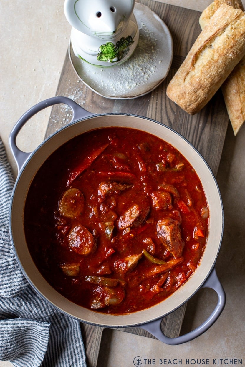 Overhead photo of a large pot filled with Italian sausage peppers, onions and red sauce